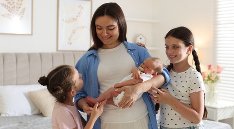 Photo of Mother with her daughters and newborn baby at home