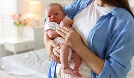 Photo of Mom with her newborn baby at home, closeup