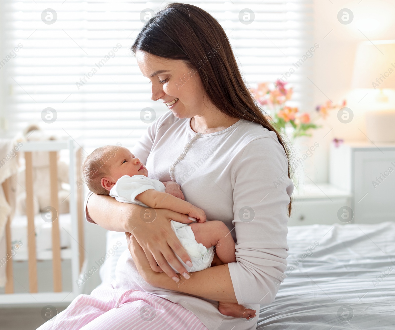Photo of Mom with her newborn baby on bed at home