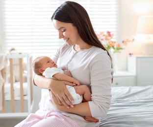 Photo of Mom with her newborn baby on bed at home