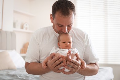 Photo of Dad kissing his newborn baby at home