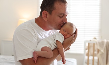 Photo of Dad kissing his newborn baby at home