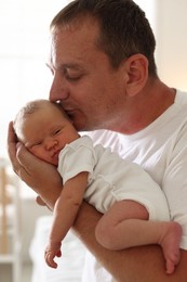Photo of Dad kissing his newborn baby at home