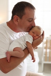 Photo of Dad kissing his newborn baby at home