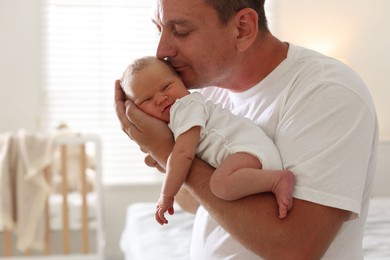 Photo of Dad kissing his newborn baby at home
