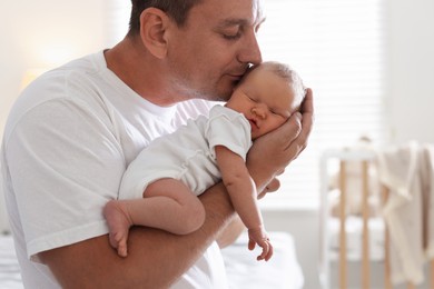 Photo of Dad kissing his newborn baby at home