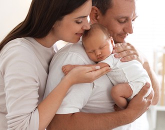 Photo of Mother and father with their newborn baby at home