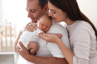 Photo of Mother and father with their newborn baby at home