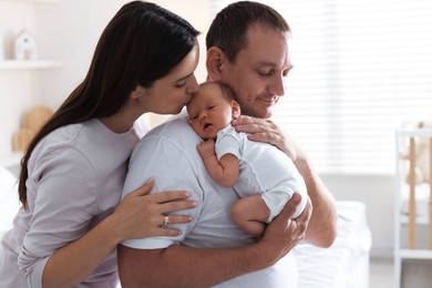 Photo of Mother and father with their newborn baby at home