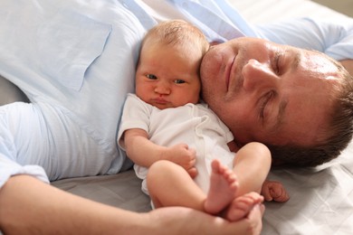 Photo of Father with his newborn baby lying on bed at home, closeup