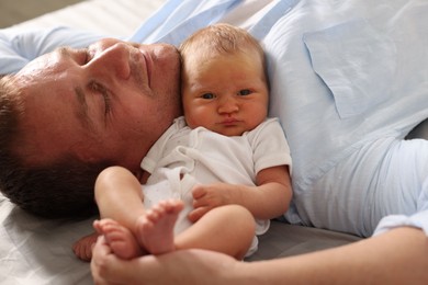 Photo of Father with his newborn baby lying on bed at home, closeup