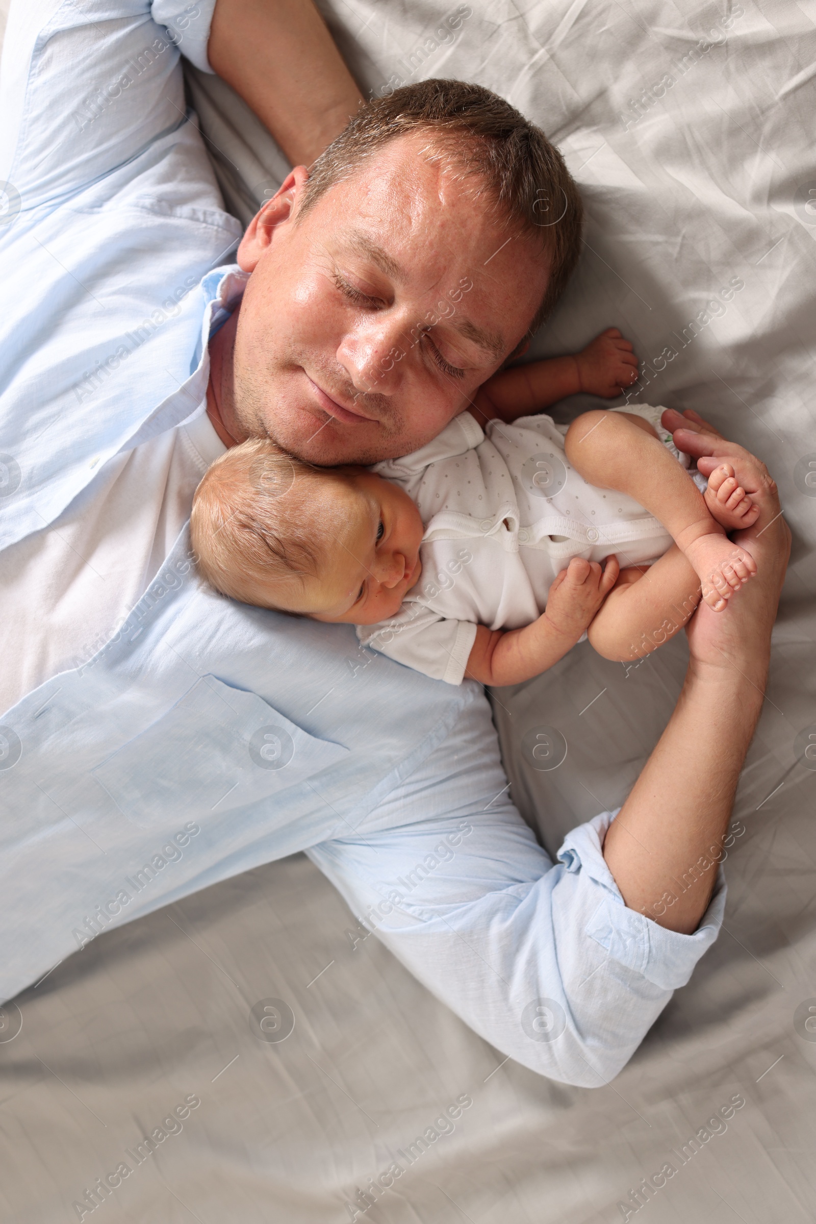 Father with his newborn baby lying on bed at home, top view Photo of Father with his newborn baby lying on bed at home, top view