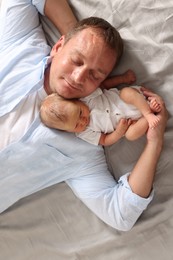 Photo of Father with his newborn baby lying on bed at home, top view