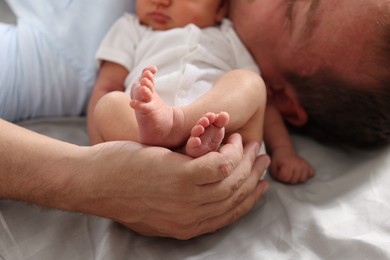 Photo of Father with his newborn baby lying on bed at home, closeup