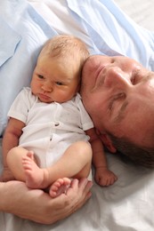 Photo of Father with his newborn baby lying on bed at home, closeup