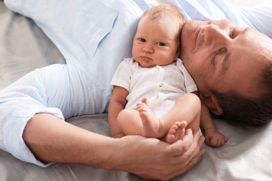Photo of Father with his newborn baby lying on bed at home, closeup