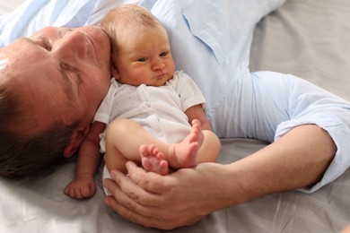 Photo of Father with his newborn baby lying on bed at home, closeup