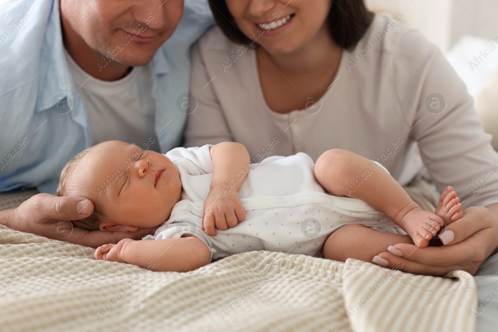 Mom and dad with their newborn baby on bed at home, closeup Photo of Mom and dad with their newborn baby on bed at home, closeup