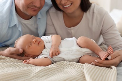 Photo of Mom and dad with their newborn baby on bed at home, closeup