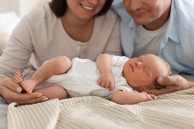 Photo of Mom and dad with their newborn baby on bed at home, closeup