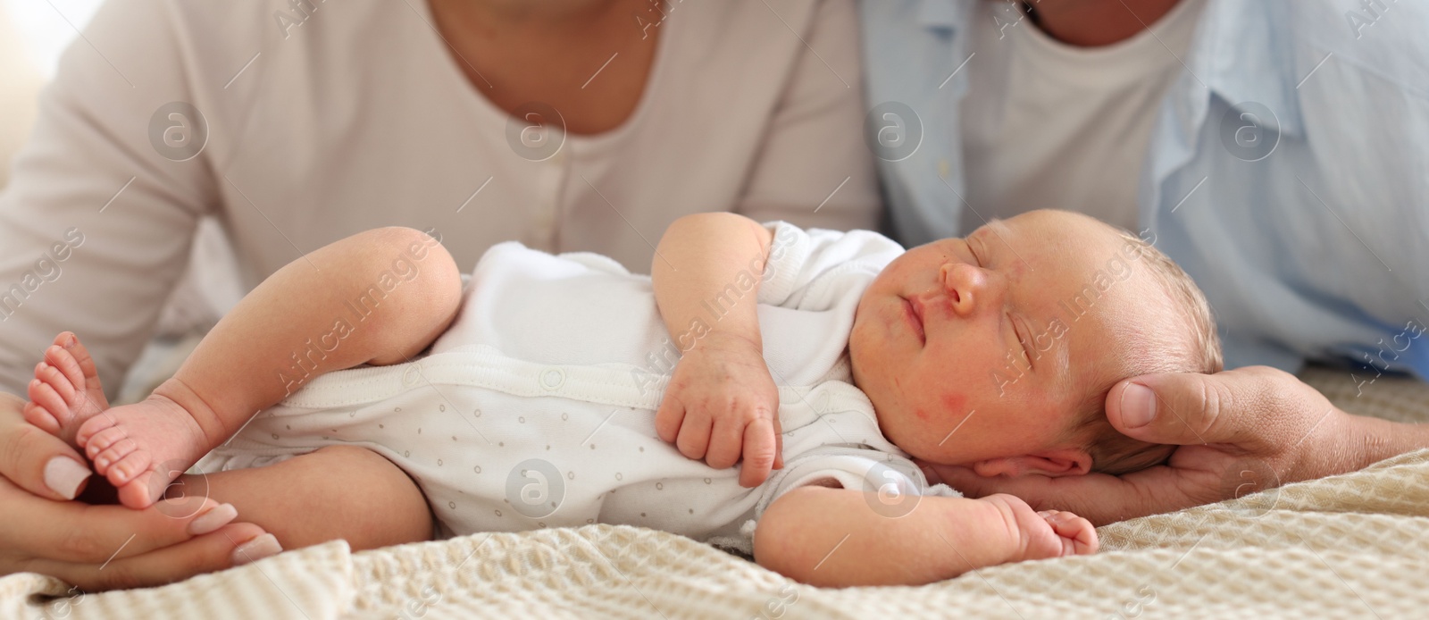 Mom and dad with their newborn baby on bed at home, closeup Photo of Mom and dad with their newborn baby on bed at home, closeup