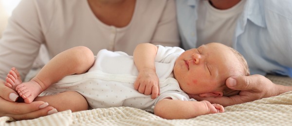 Photo of Mom and dad with their newborn baby on bed at home, closeup