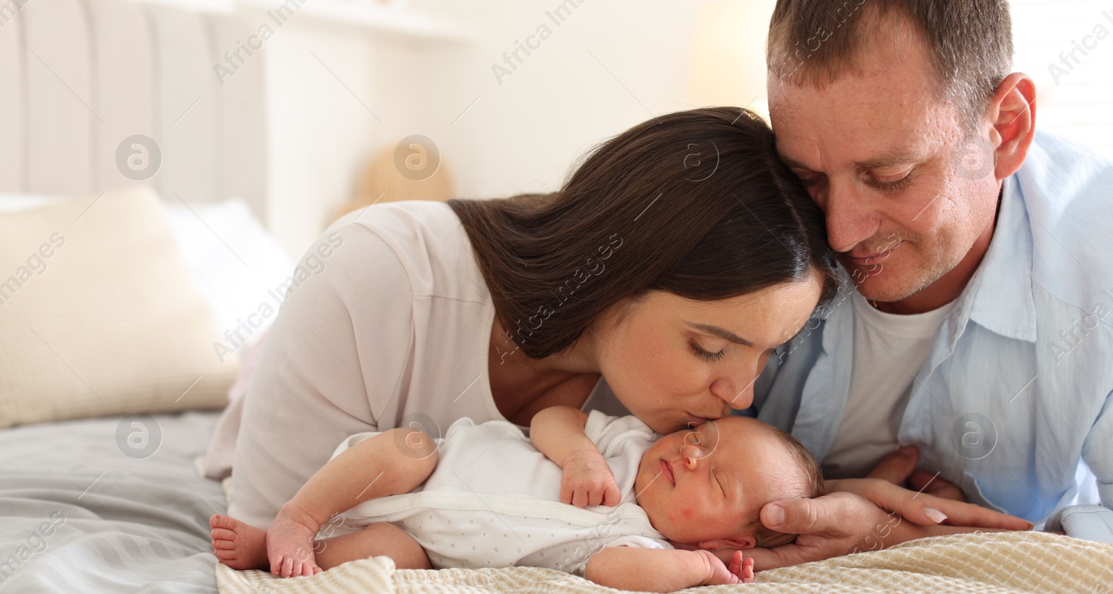 Mom and dad with their newborn baby on bed at home Photo of Mom and dad with their newborn baby on bed at home