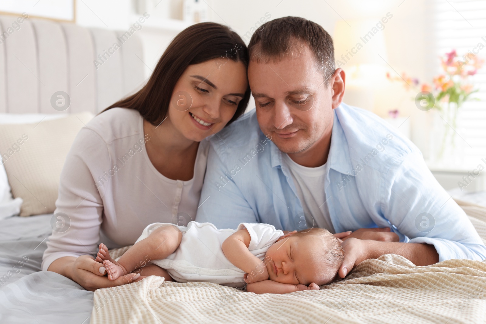 Mom and dad with their newborn baby on bed at home Photo of Mom and dad with their newborn baby on bed at home