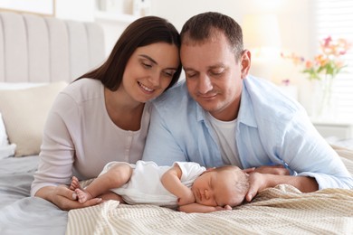 Photo of Mom and dad with their newborn baby on bed at home