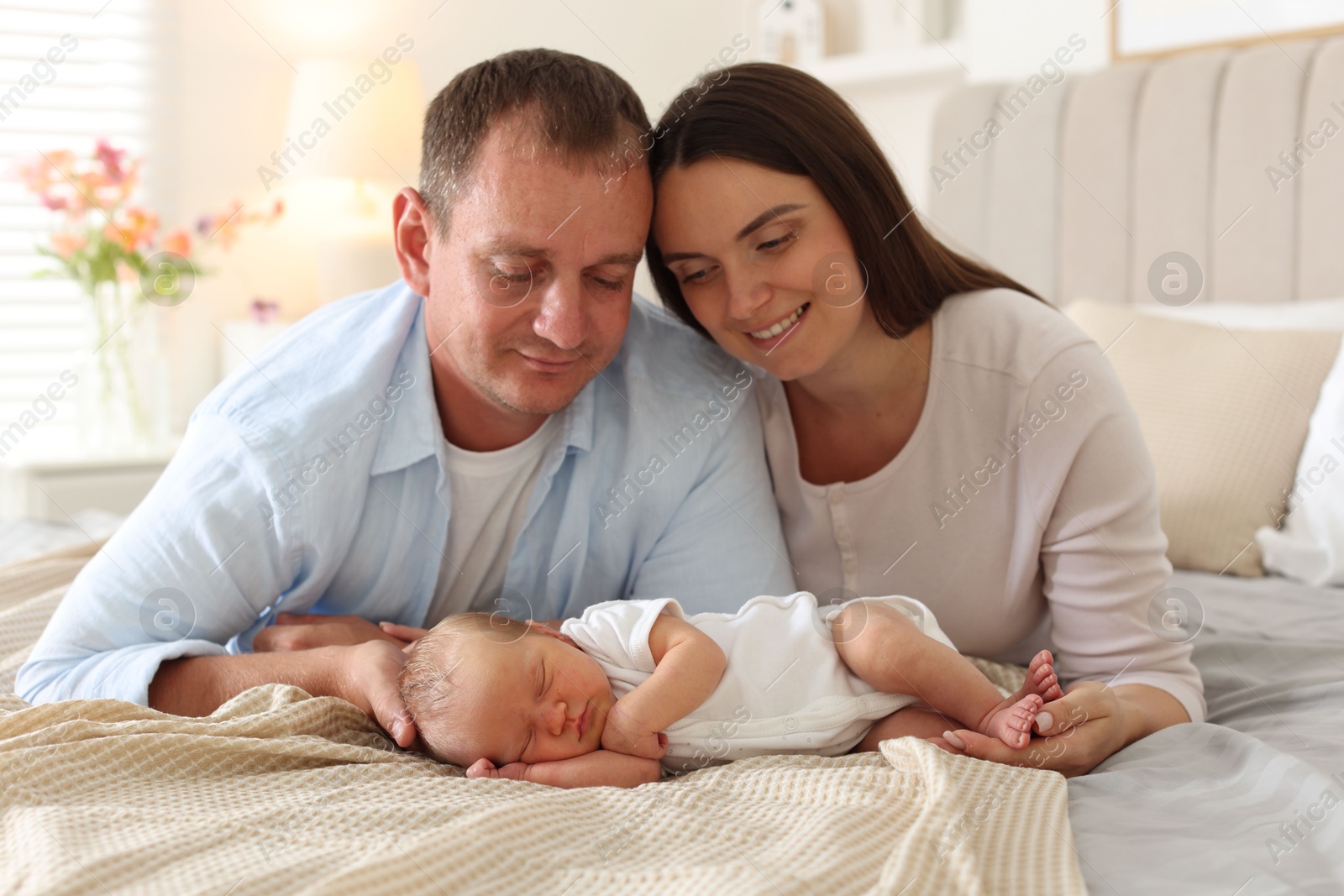 Mom and dad with their newborn baby on bed at home Photo of Mom and dad with their newborn baby on bed at home
