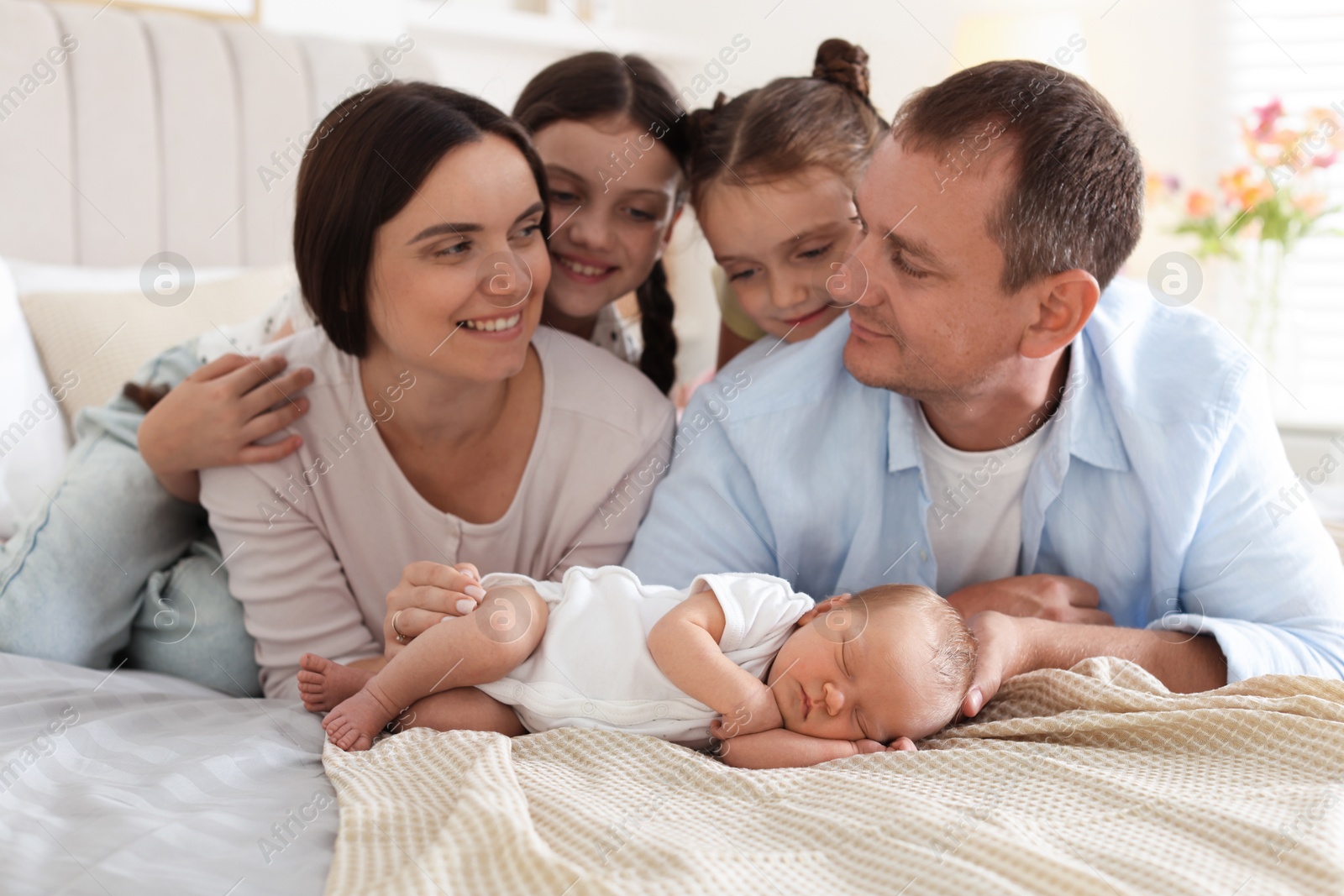 Happy family with newborn baby on bed at home Photo of Happy family with newborn baby on bed at home