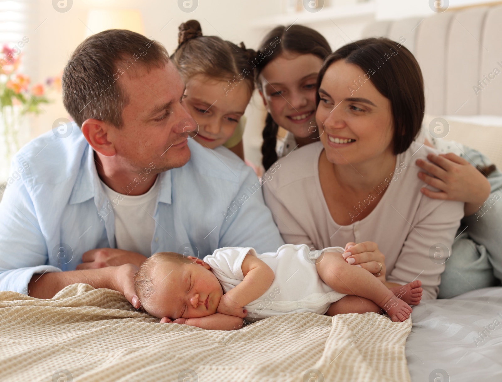 Happy family with newborn baby on bed at home Photo of Happy family with newborn baby on bed at home