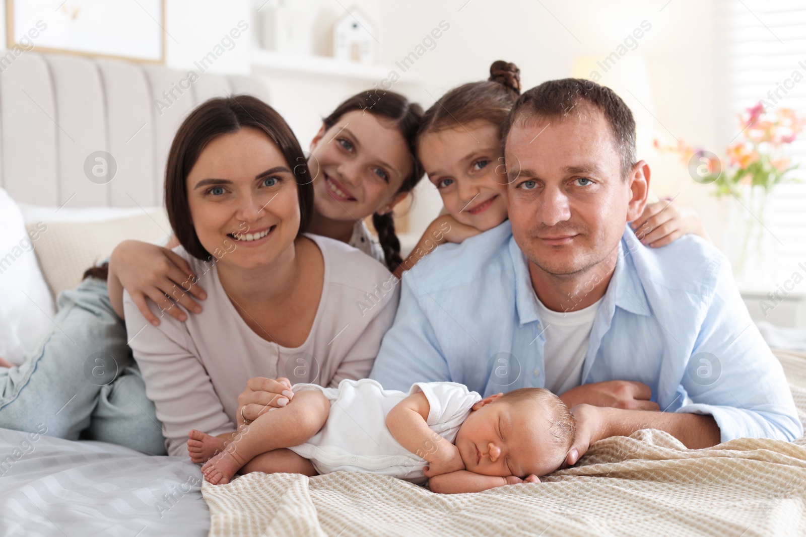 Happy family with newborn baby on bed at home Photo of Happy family with newborn baby on bed at home