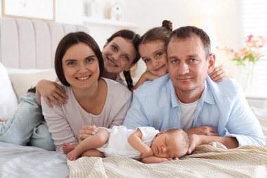 Photo of Happy family with newborn baby on bed at home