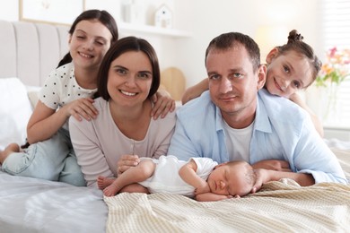 Photo of Happy family with newborn baby on bed at home