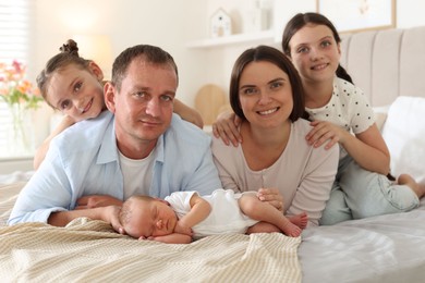 Photo of Happy family with newborn baby on bed at home