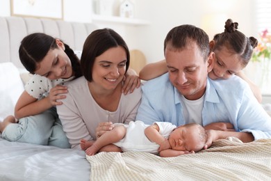 Photo of Happy family with newborn baby on bed at home