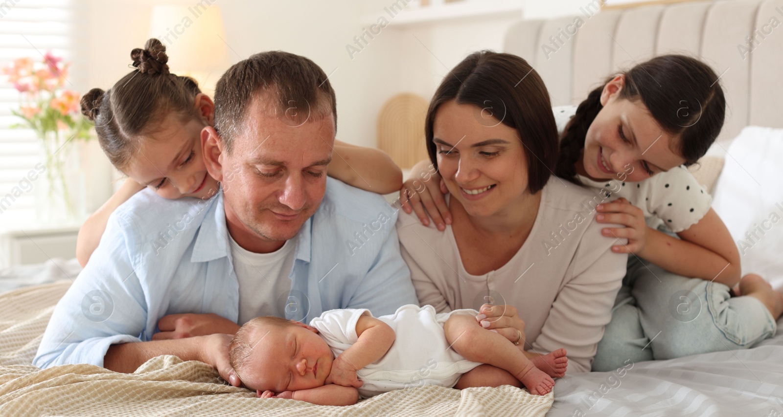Happy family with newborn baby on bed at home Photo of Happy family with newborn baby on bed at home