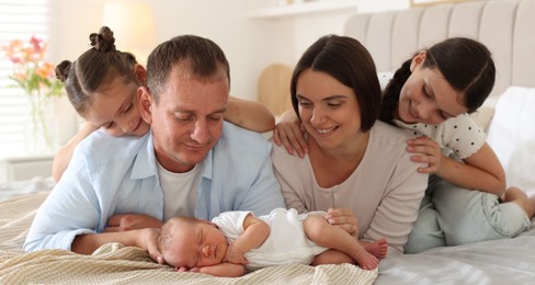 Photo of Happy family with newborn baby on bed at home