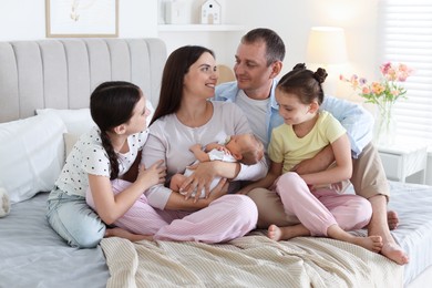 Photo of Happy family with newborn baby on bed at home