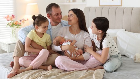 Photo of Happy family with newborn baby on bed at home