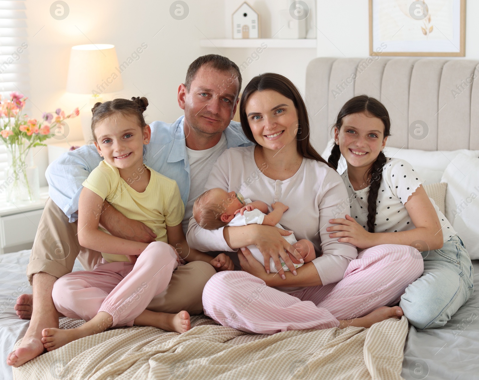 Happy family with newborn baby on bed at home Photo of Happy family with newborn baby on bed at home