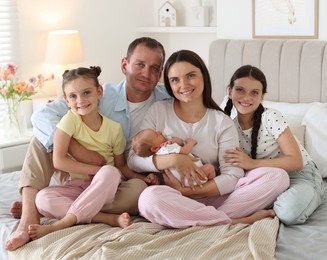 Photo of Happy family with newborn baby on bed at home
