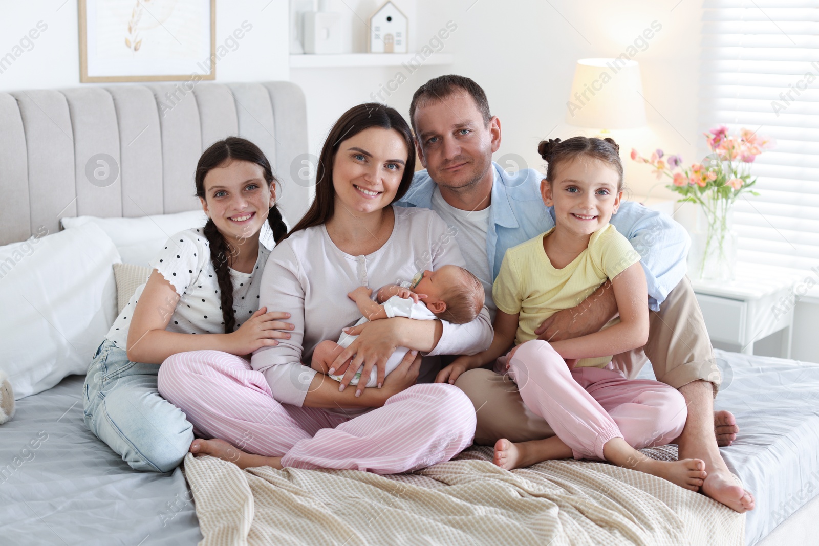 Happy family with newborn baby on bed at home Photo of Happy family with newborn baby on bed at home
