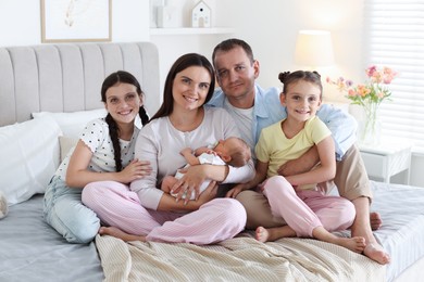 Photo of Happy family with newborn baby on bed at home