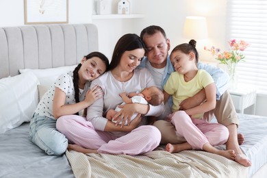 Photo of Happy family with newborn baby on bed at home