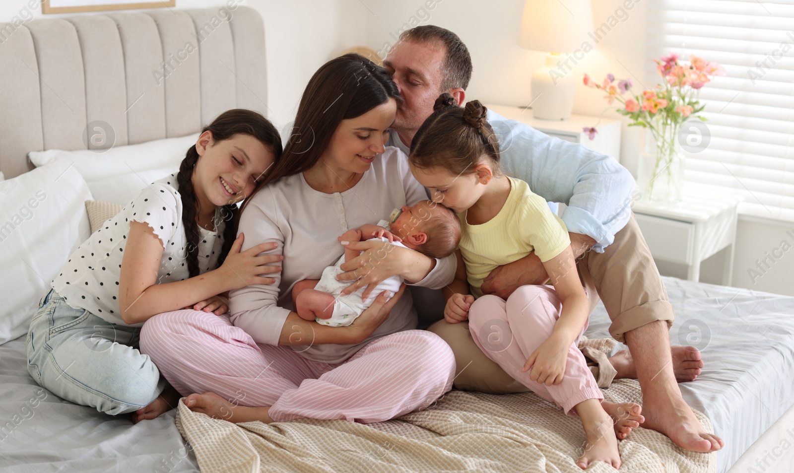 Happy family with newborn baby on bed at home Photo of Happy family with newborn baby on bed at home