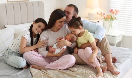 Photo of Happy family with newborn baby on bed at home