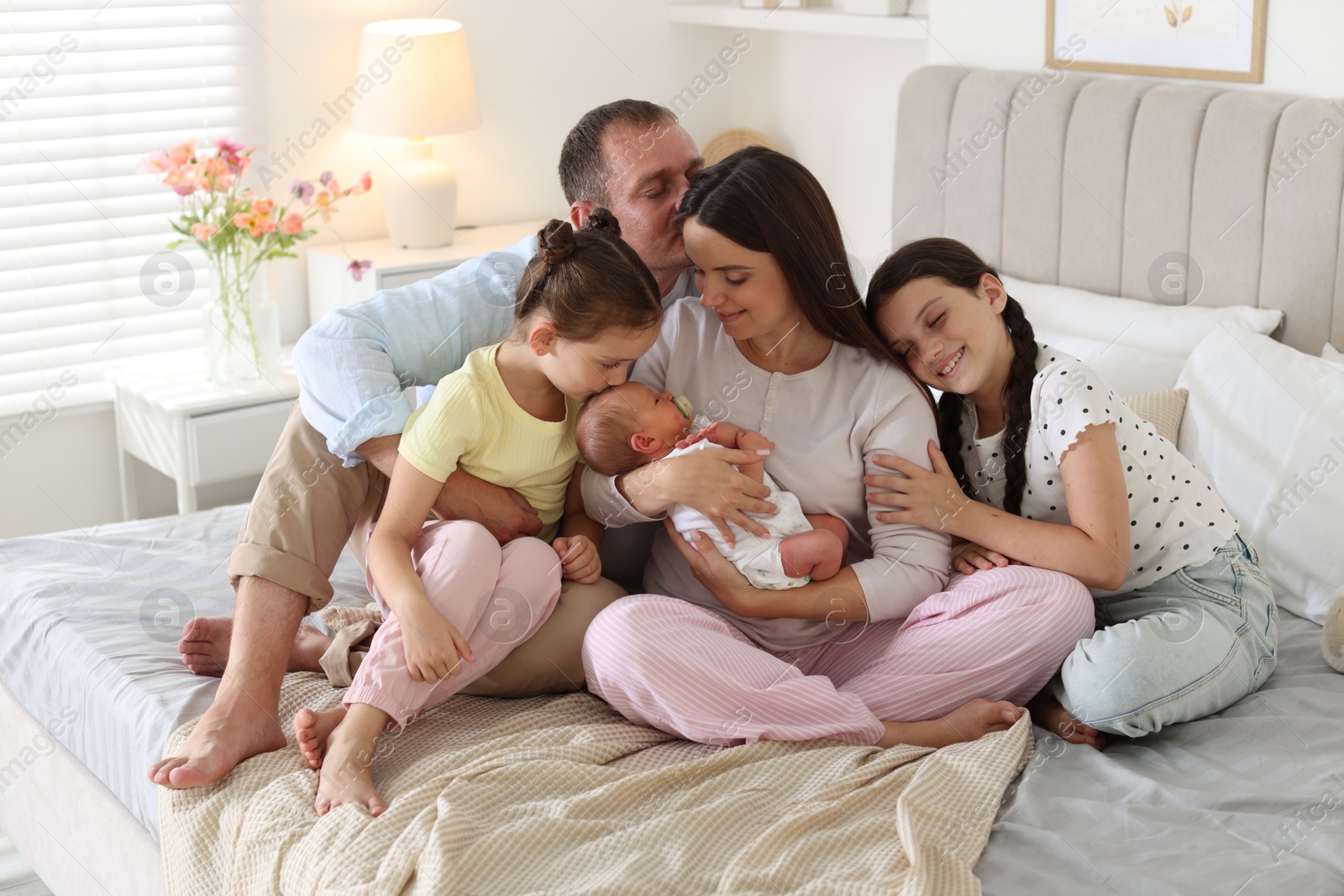 Happy family with newborn baby on bed at home Photo of Happy family with newborn baby on bed at home