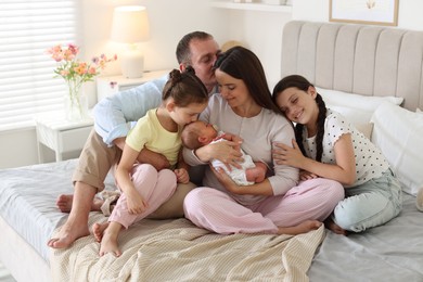 Photo of Happy family with newborn baby on bed at home